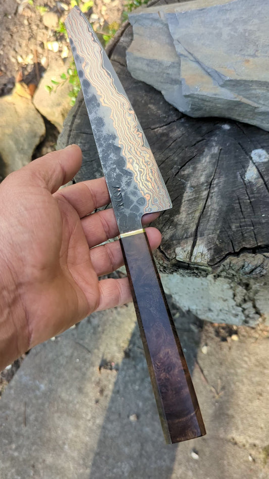 Hand-forged Yu-Shoku VG10w core Mokume clad (rainbow damascus). Burr Elm with brass bolster handle